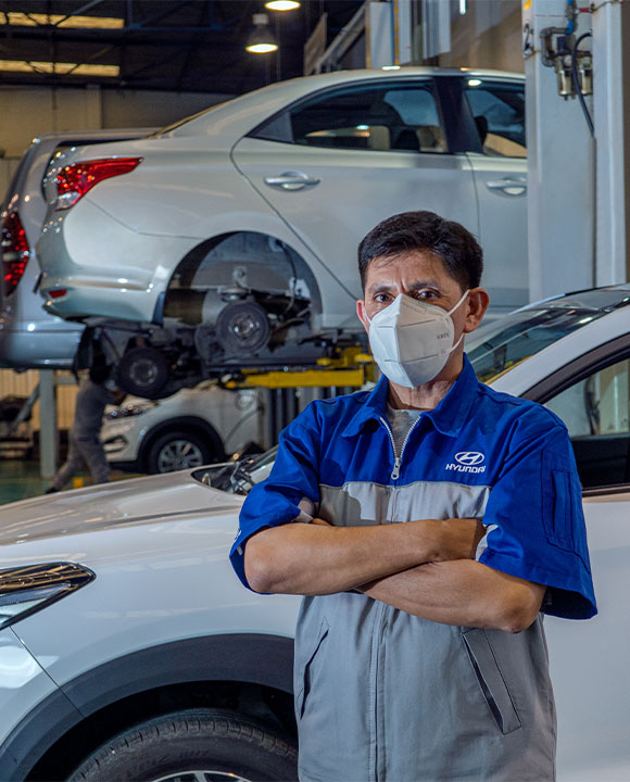 Mecánico con cubrebocas y detrás un carro Hyundai