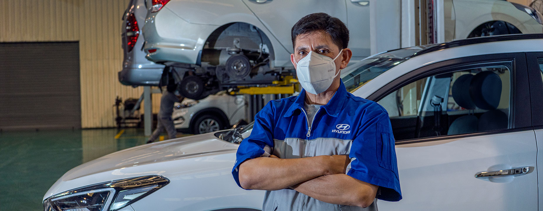 Mecánico con cubrebocas y detrás un carro Hyundai
