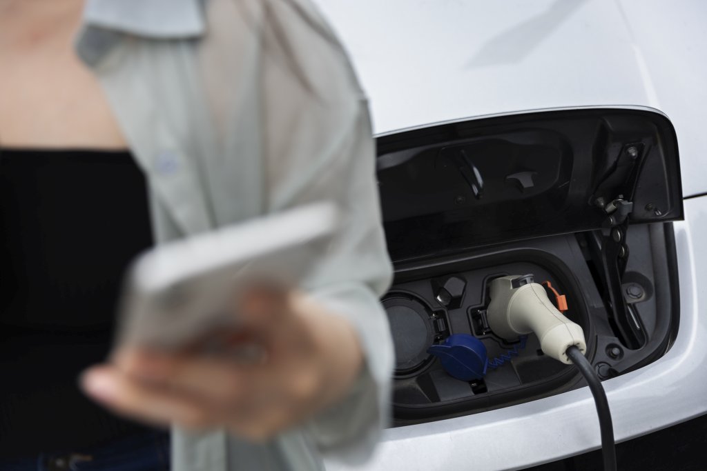 mujer en estación de carga de batería de carro eléctrico