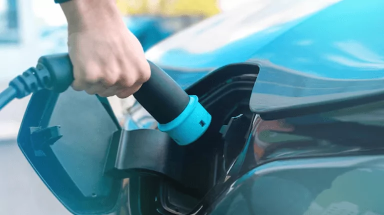 persona cargando la batería de un carro eléctrico